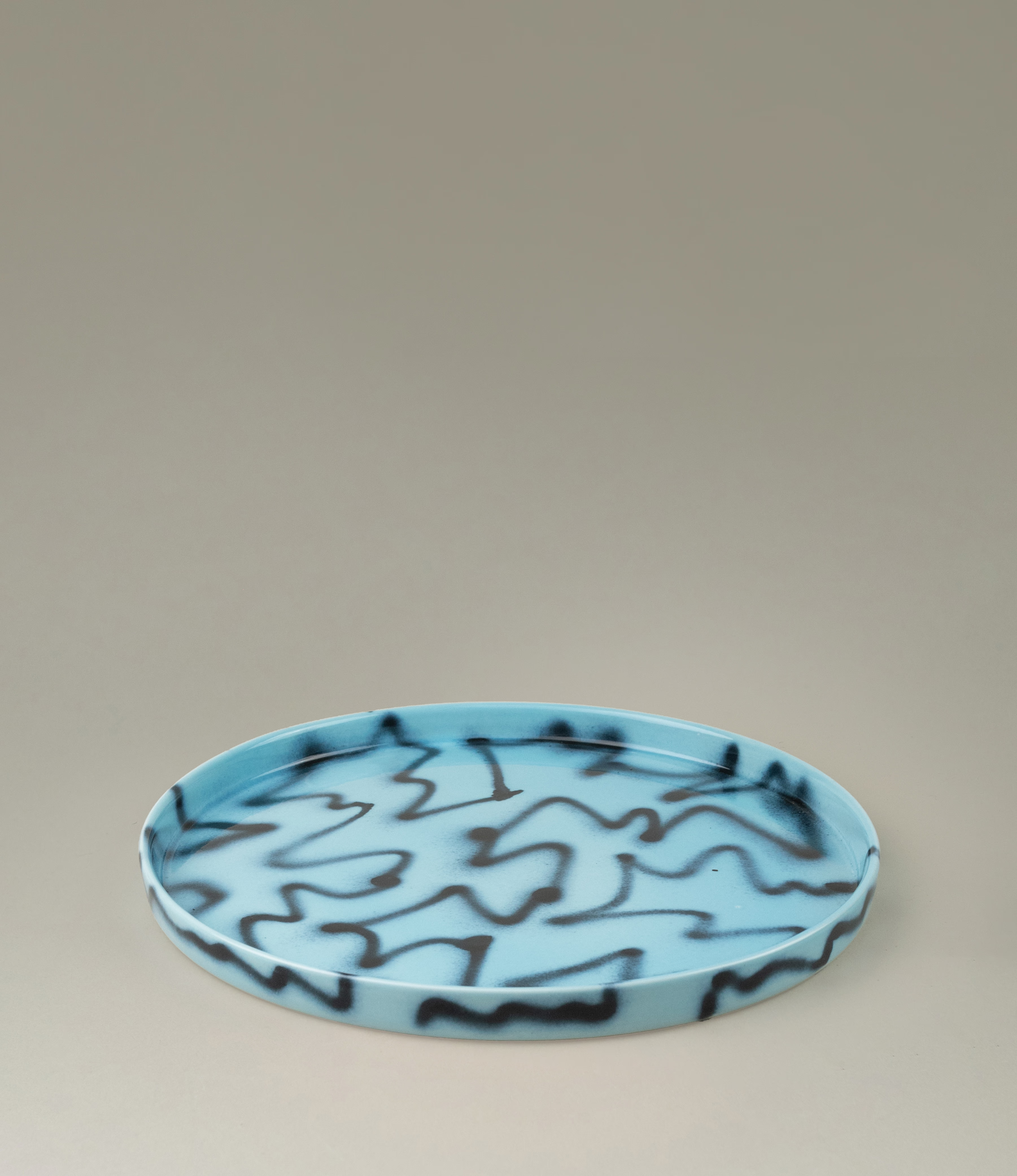 Blue Pizza Tray from Frizbee Ceramics. The tray is coming in the soothing light blue color matched with the contrasting black zig-zag pattern.