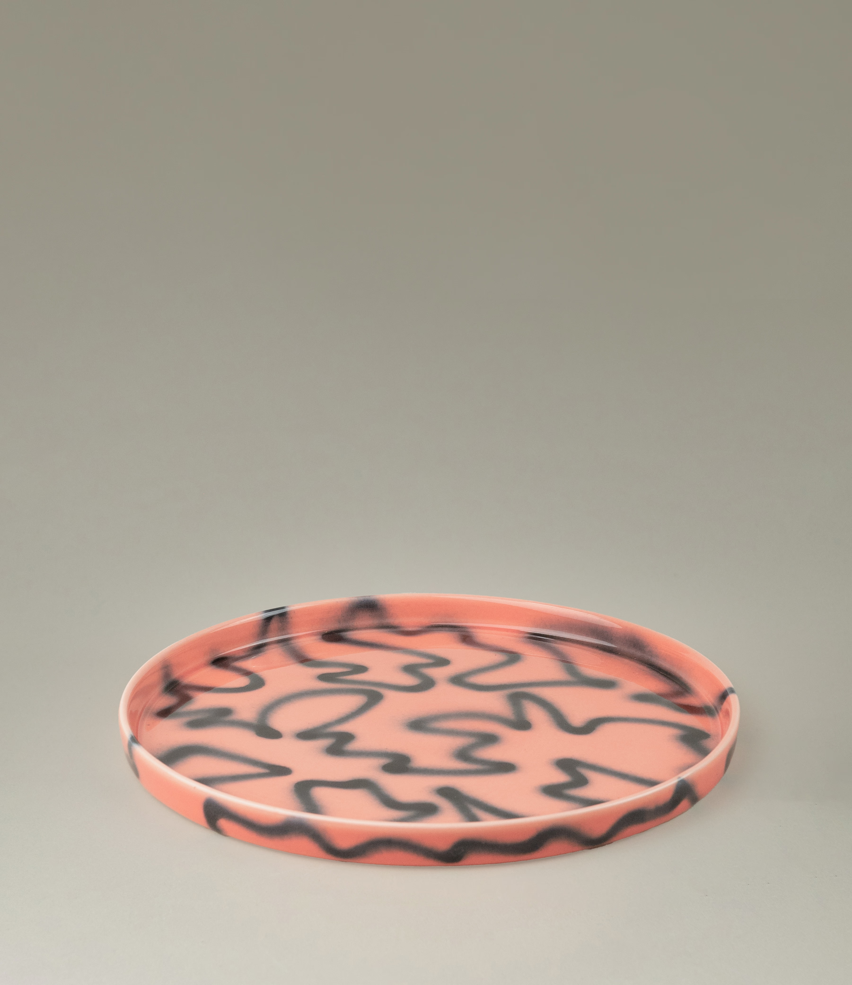 Peach Pizza Tray from Frizbee Ceramics. The tray is coming in the soothing peach color matched with the contrasting black zig-zag pattern.