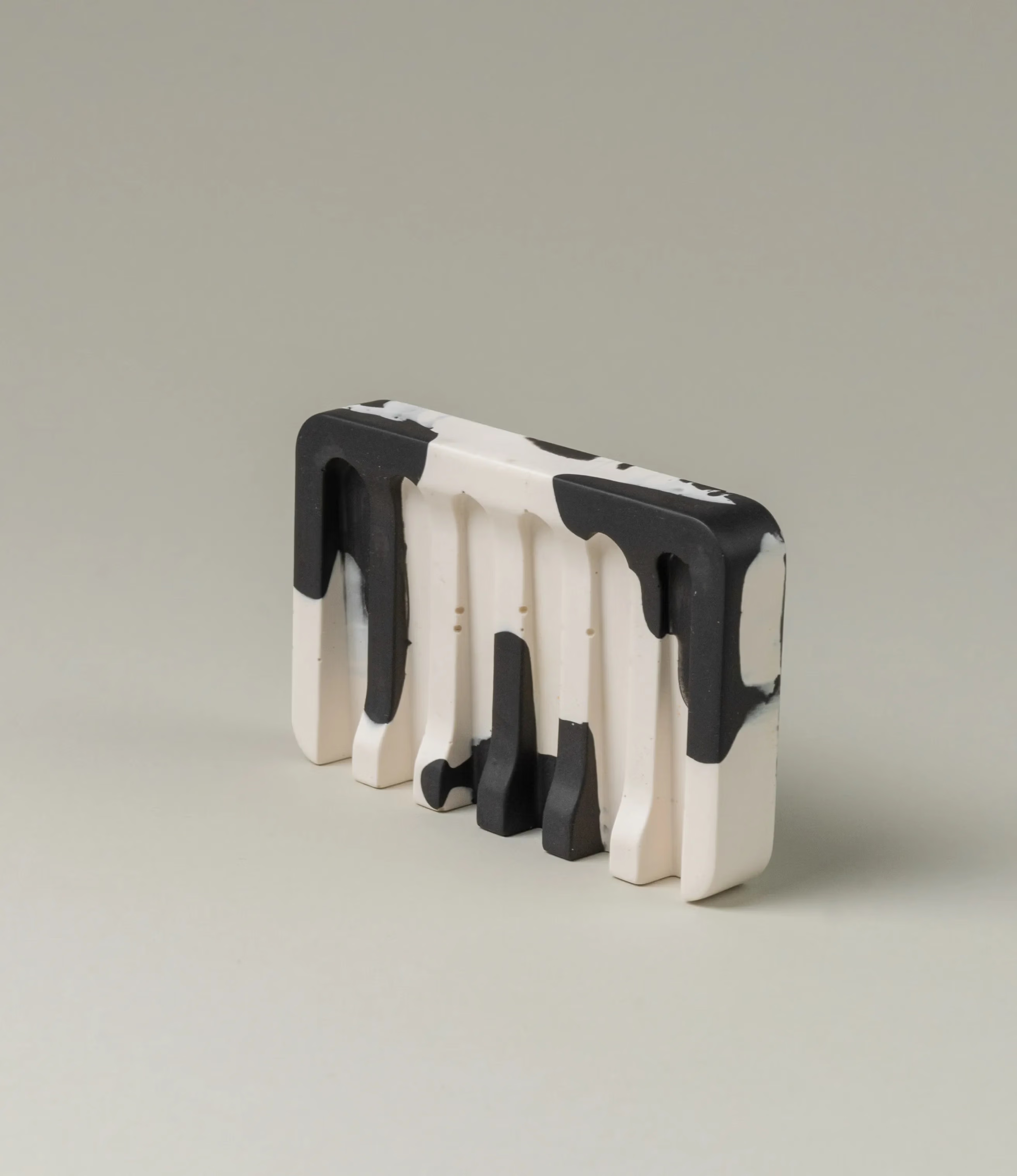 Soap Holder from Gritful Homeware in the minimalist color pairing of black and white. The soap dish has a rectengular shape which contrasts the pattern of the item, which is more organic and resembles paint splashes.