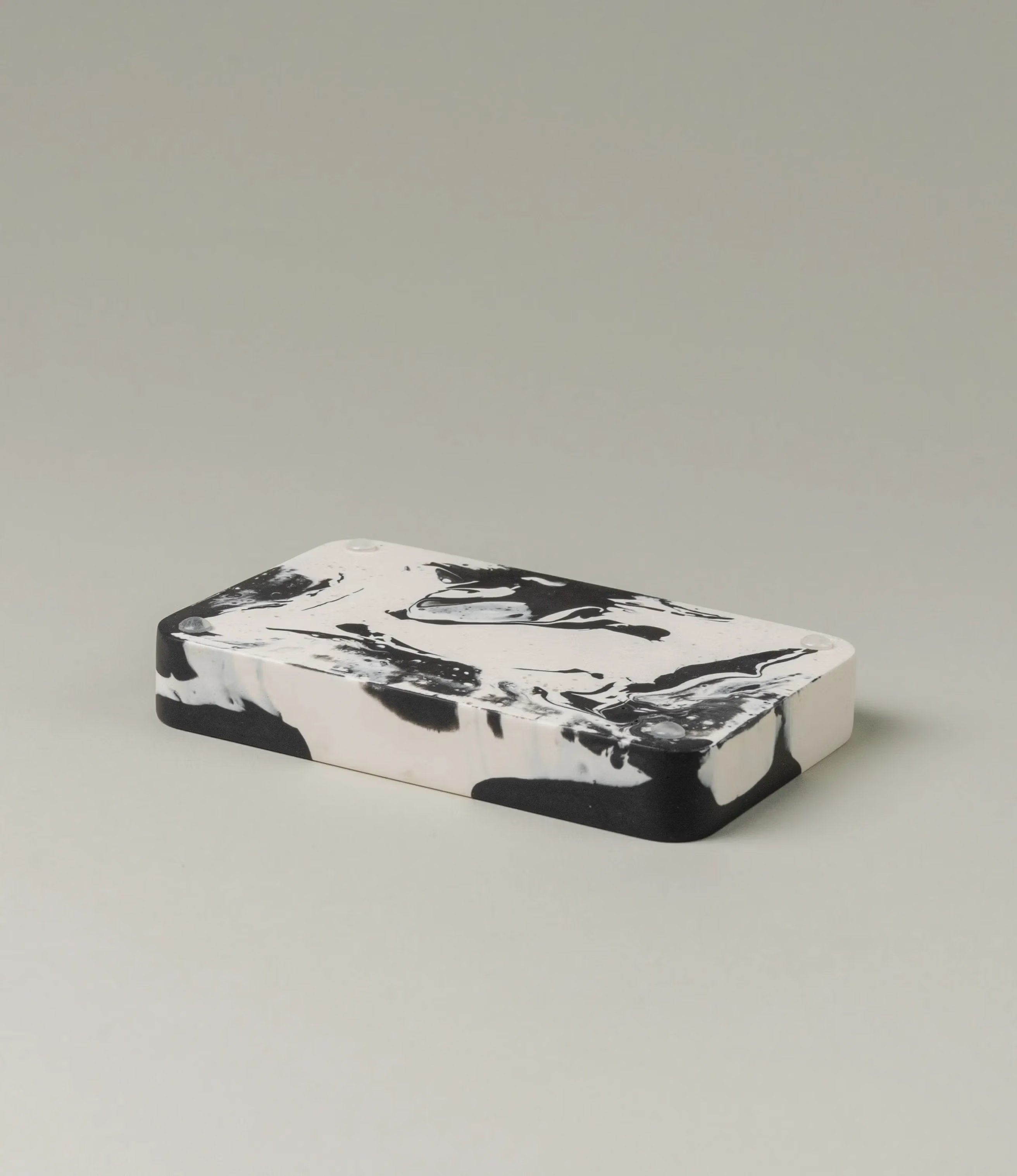 Soap Holder from Gritful Homeware in the minimalist color pairing of black and white. The soap dish has a rectengular shape which contrasts the pattern of the item, which is more organic and resembles paint splashes.