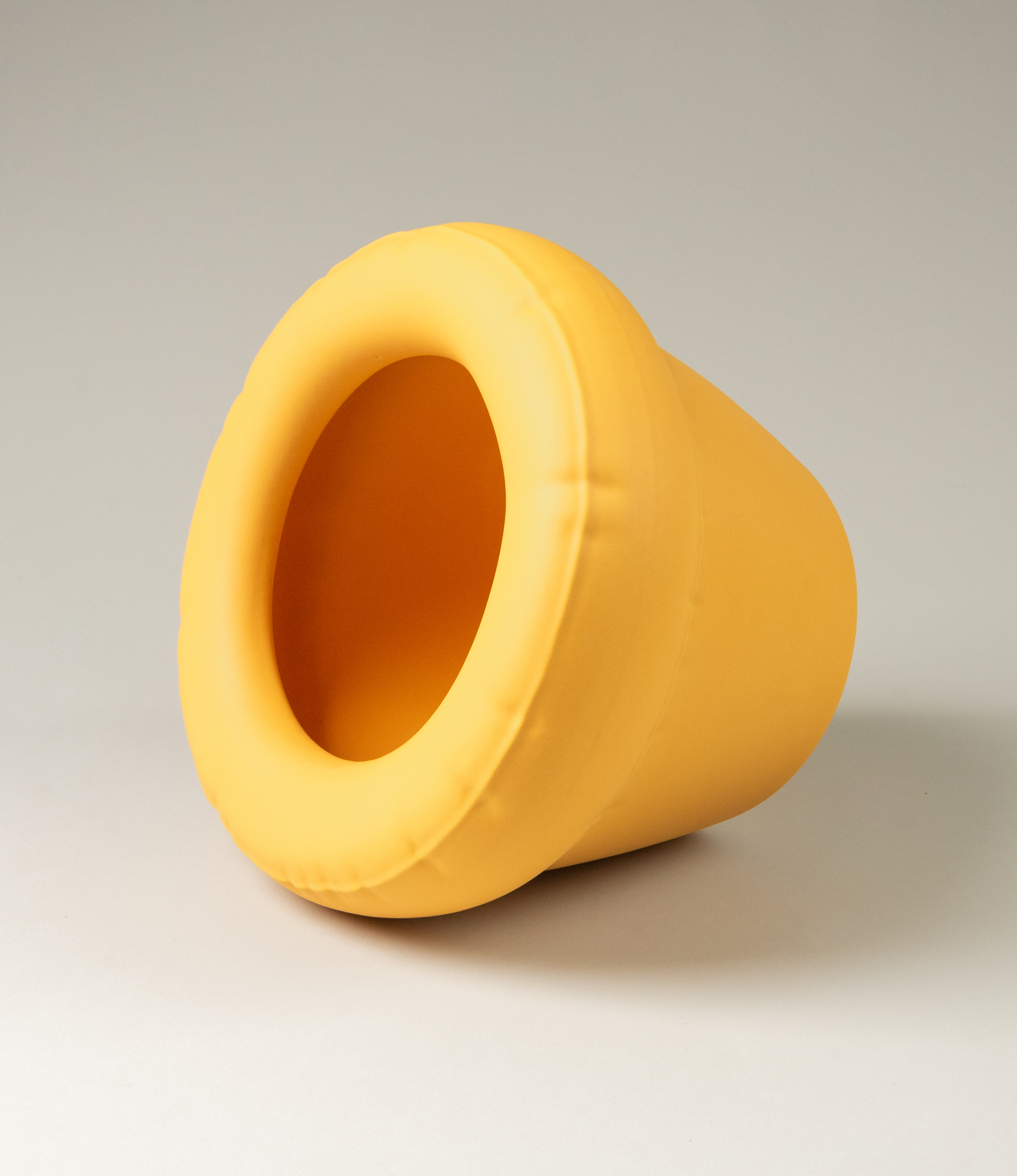 Homestudyo planter pierre in Yolk (yellow) color. The p[icture shows the product sideways and with a view towards its interior. The planter design looks like and inflatable ballon although it is made of ceramics.