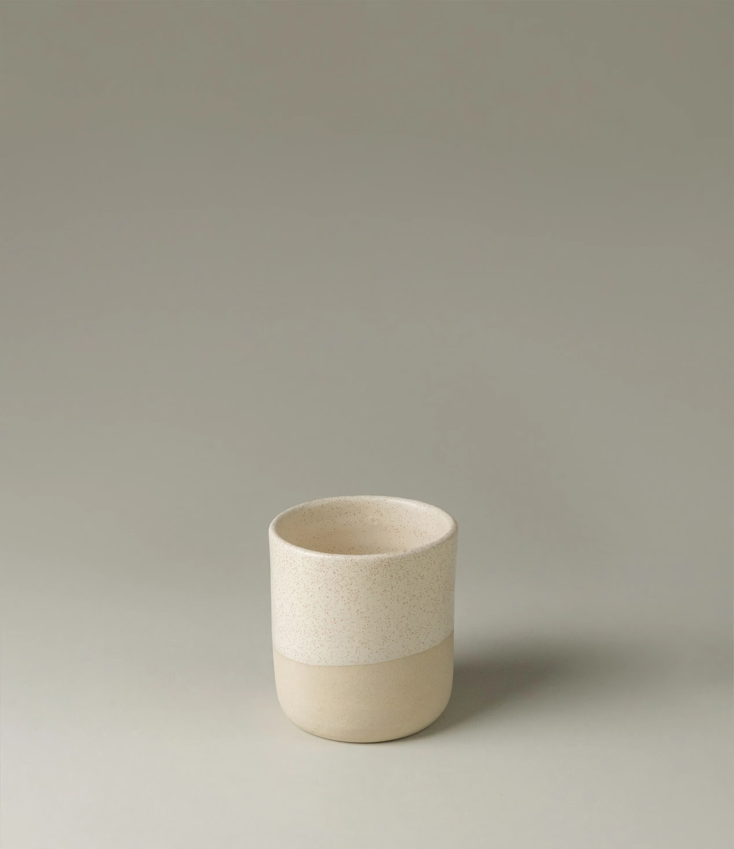 This ceramic cup was envisioned by Ocactuu. The light colors match any kind of hot drink of your choice. The bottom of the cup has a rougher texture with a slightly darker shade of beige, while the upper part has a subtle spotted pattern with an off white base. The shape of the item is simple yet sophisticated. The cups come in a set of two.