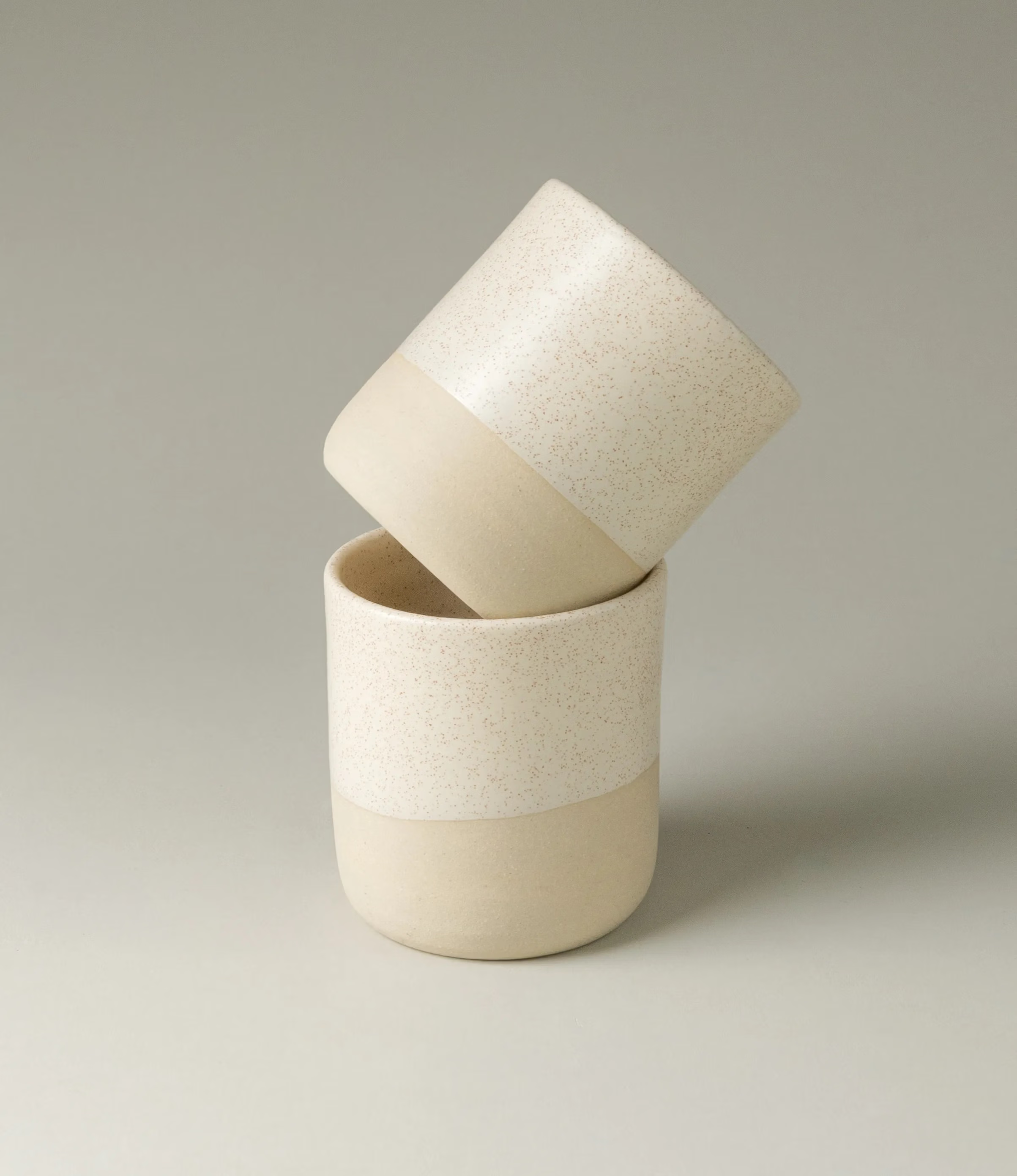 This ceramic cup was envisioned by Ocactuu. The light colors match any kind of hot drink of your choice. The bottom of the cup has a rougher texture with a slightly darker shade of beige, while the upper part has a subtle spotted pattern with an off white base. The shape of the item is simple yet sophisticated. The cups come in a set of two.