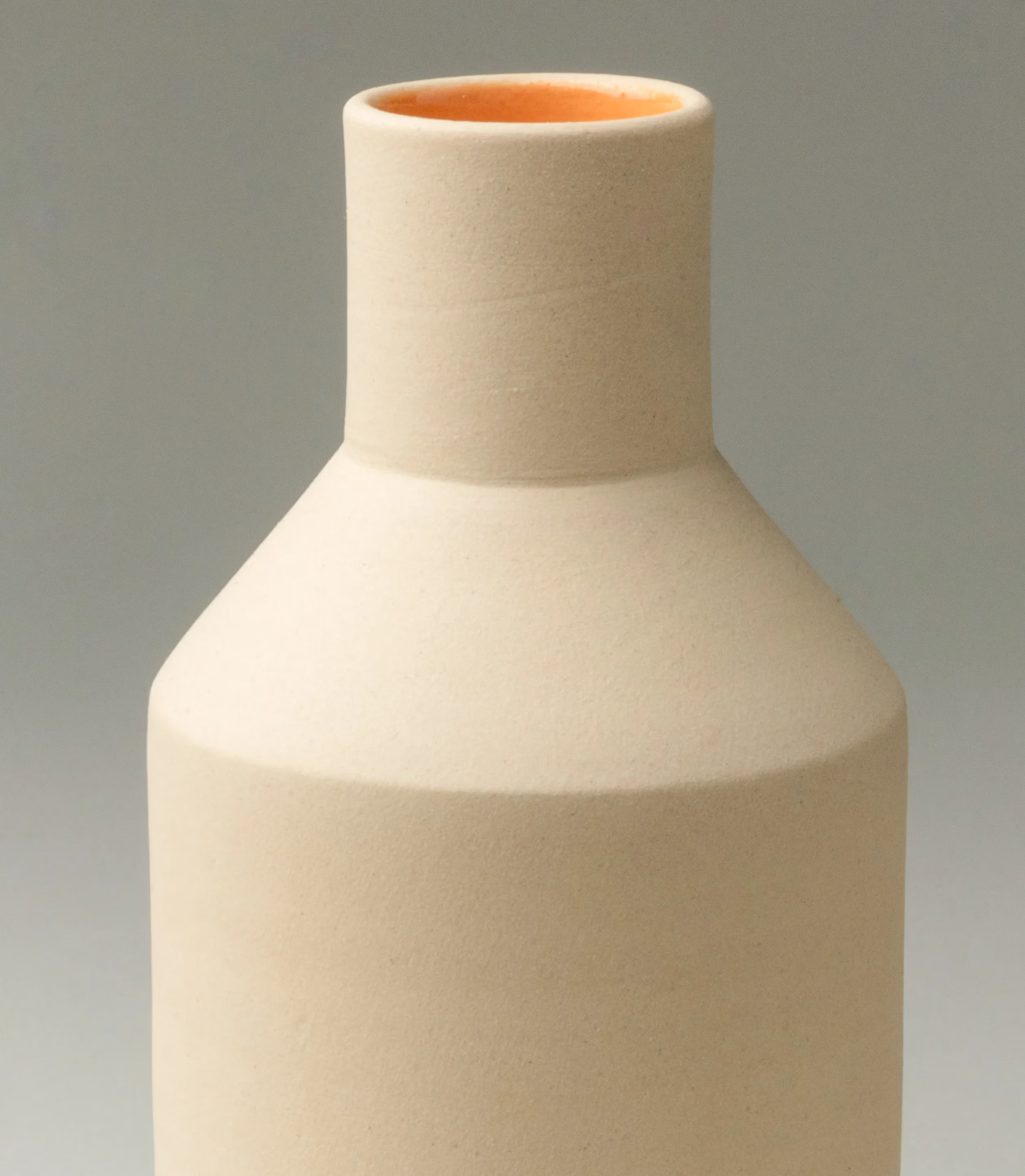 Natural Orange Vase was designed by Ocactuu. The item has a champagne color matte finish on the outside and a bright orange glossy glaze on the inside. The product is very geometrical and it has clear edges.