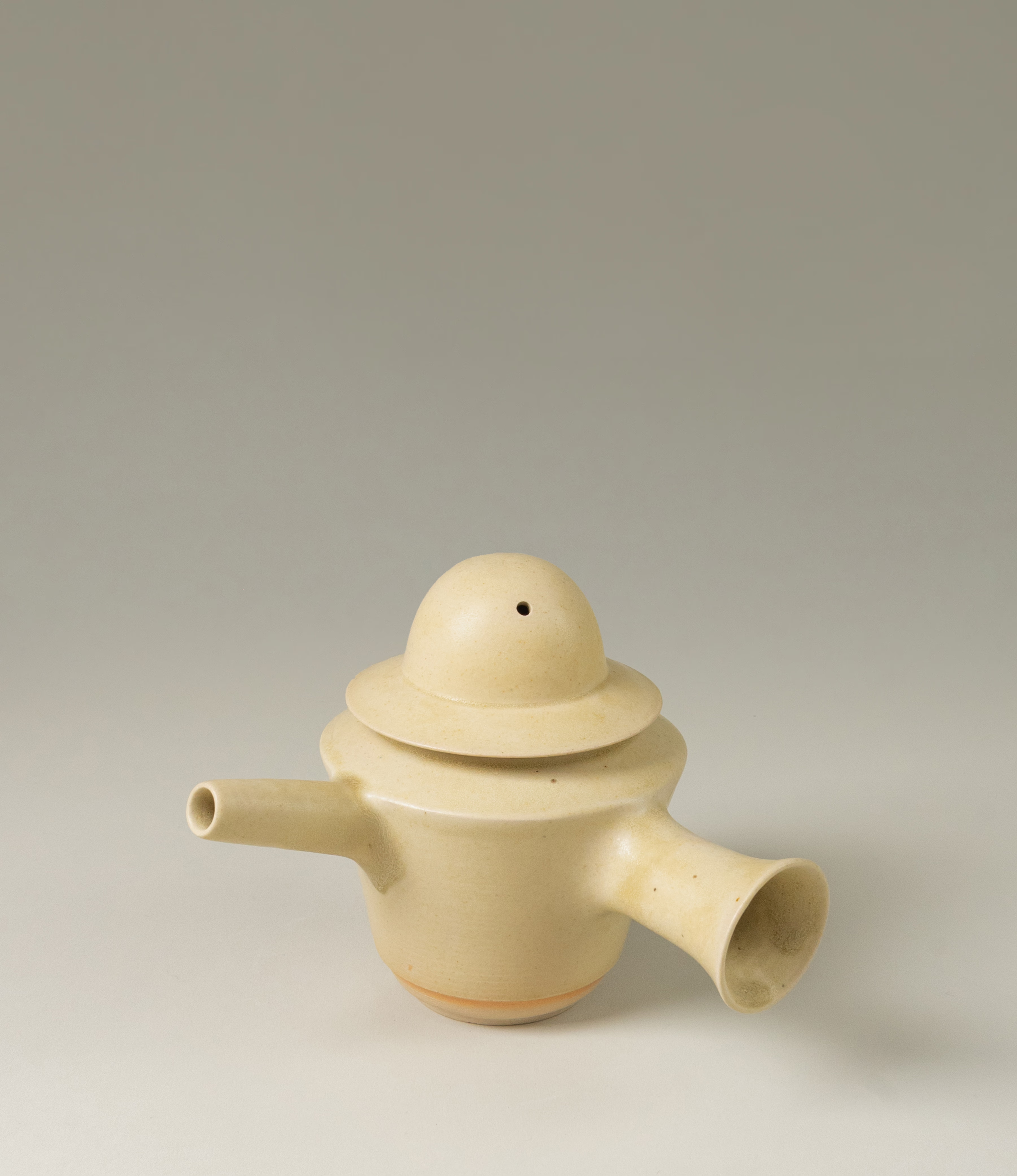 A special teapot from Omni Ceramics. The product adds a spice to the Omni tea collection. The lid of the teapot resembles a hat. The item comes in a light beige color, and with the unique painted orange gradient ring on the lower part of the product.