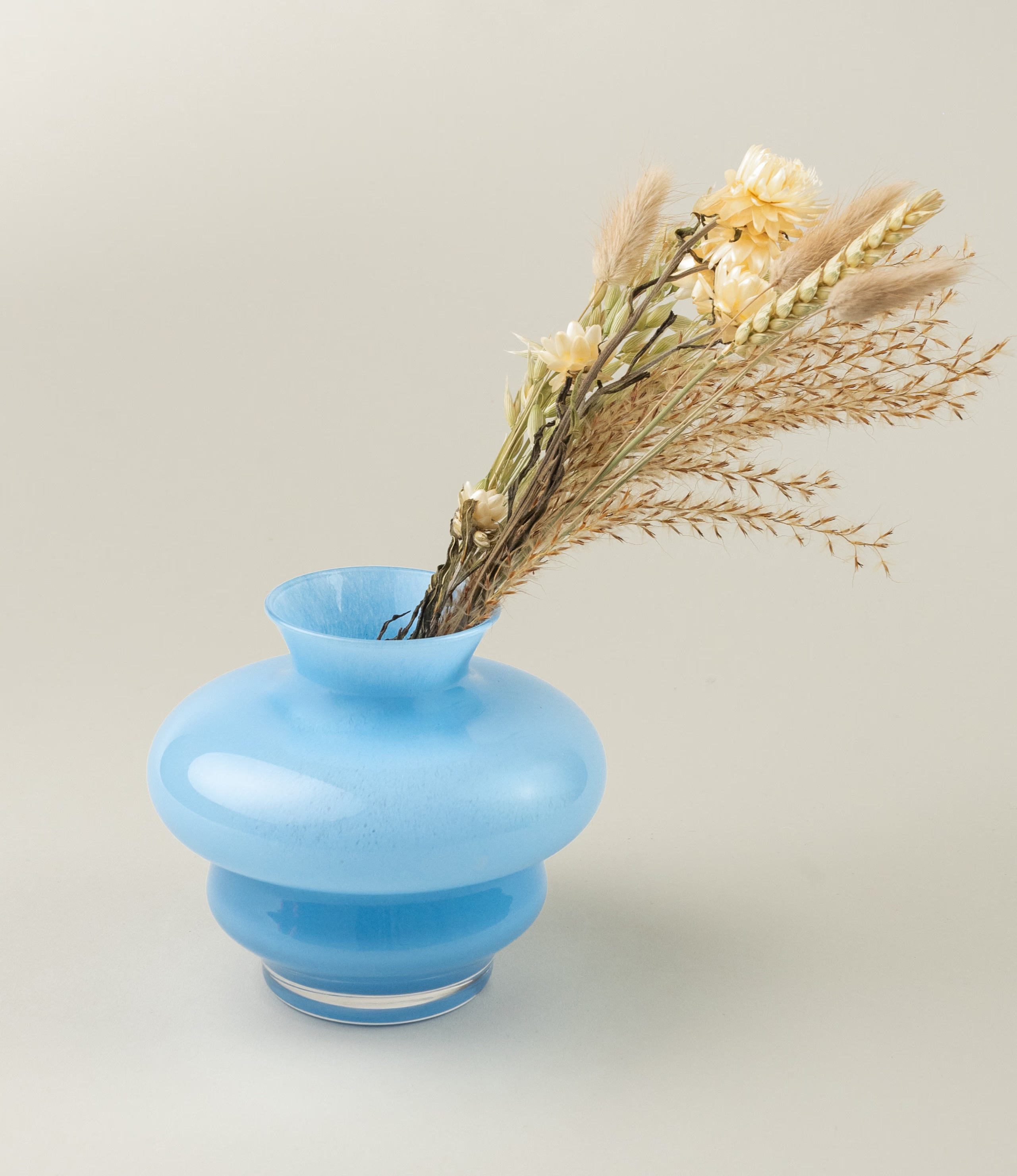 Curve Vase Mini from Stences comes in a Blue color. It is a cury glass vase, which makes your interior pop. On this picture you can see the product with our natural dried flowers.