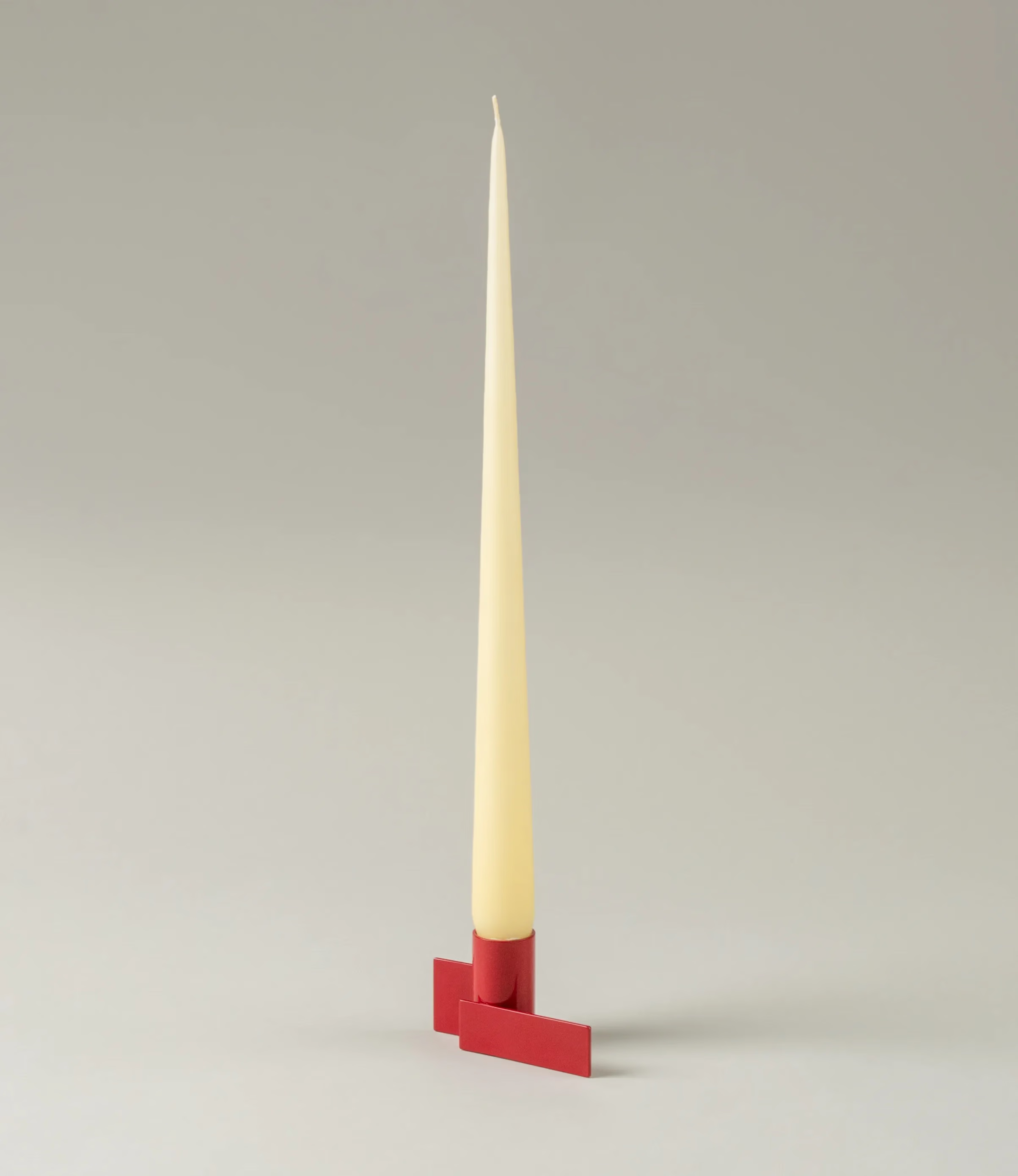 Icon Iysestage 01 from Stences is a candleholder made for taper candles. This picture shows the red variant of this item. The steel material has a glossy surface which emphasize the soft geometric shapes of the product in question. It is captured in use with Ester&Erik's Taper Candle in a Buttermilk hue.